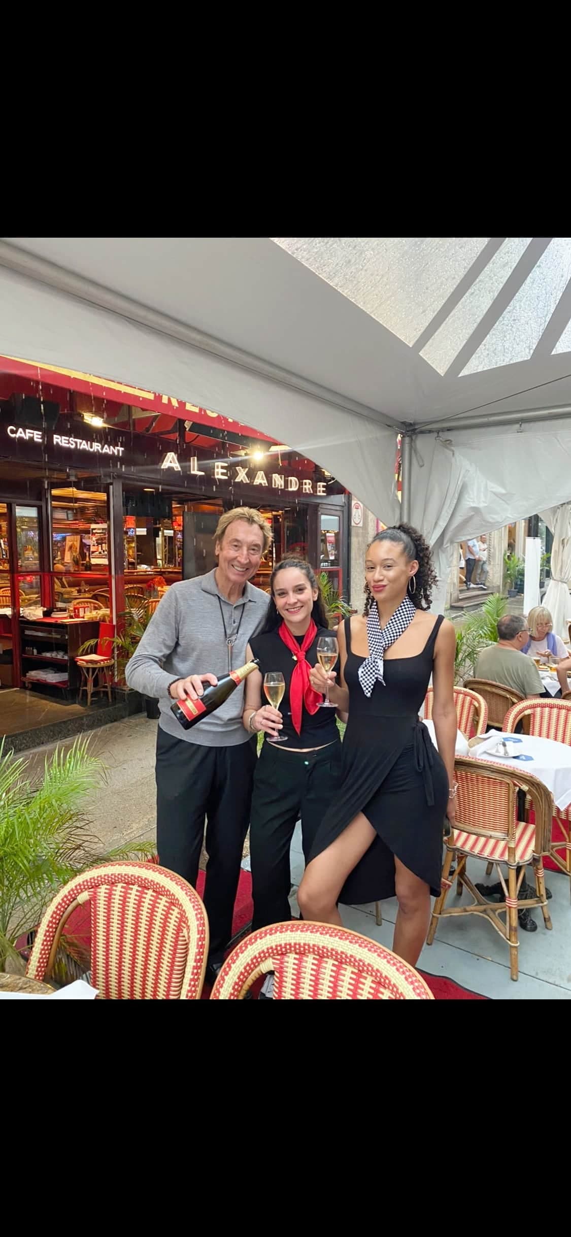 Alain Creton, propriétaire du restaurant Chez Alexandre et fils, sur la rue Peel à Montréal, verse des coupes de champagne à la serveuse Émeline Gaspard et à l’hôtesse Juliana Barrett sur la terrasse.