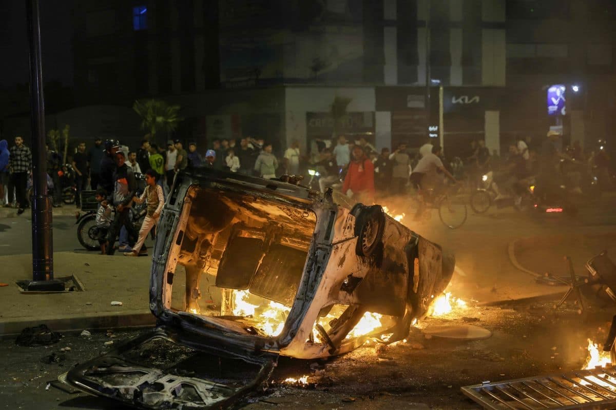 Des gens regardent un véhicule de police incendié lors d’une manifestation menée par des jeunes exigeant des réformes dans les secteurs de la santé et de l’éducation à Sale, le 1er octobre 2025.