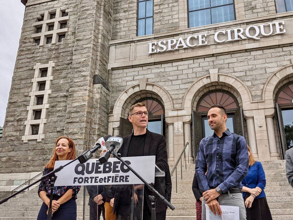 Le chef de Québec forte et fière, Bruno Marchand (au centre), et son nouveau candidat dans le district de Limoilou, Florent Tanlet, devant l'École de cirque de Québec, vendredi. Le parti municipal s'est engagé à verser un montant de 1,8 million $ à l'organisme pour l'aider à réaliser son projet d'agrandissement.
