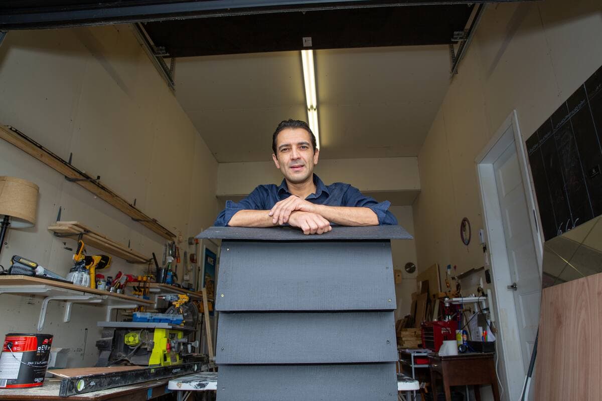 Stephen Morel dans son atelier en Montérégie où il construit ses cabanes pour chauves-souris, comme celle sur laquelle il est accoudé.