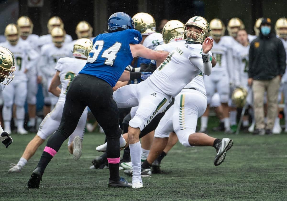 (4) Anthony Robichaud (SHE) qui est poussé par (94) Philippe Lemieux-Cardinal (MTL) lors du premier quart du match de football universitaire entre le Vert & Or de l’Université de Sherbrooke et des Carabins de l’Université de Montréal au Stade CEPSUM le samedi 2 octobre 2021.