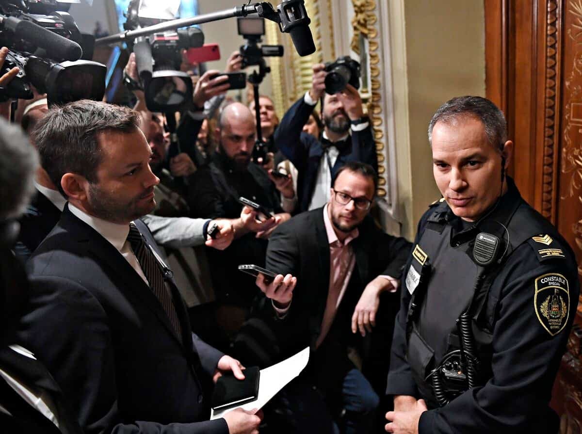 M. St-Pierre Plamondon se fait barrer le chemin par un constable spécial, sous l’œil attentif des journalistes.