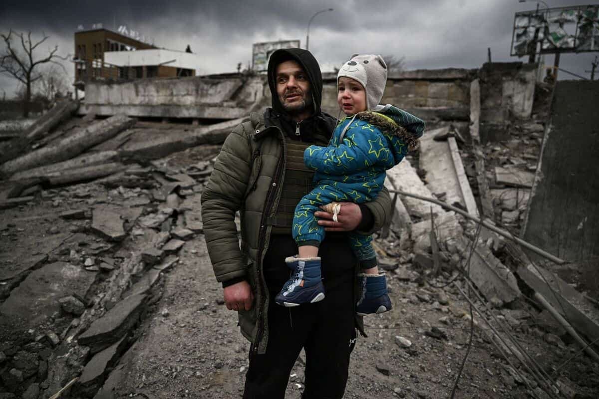 Un homme tient dans ses bras un enfant alors qu'il s'apprête à quitter la ville d'Irpin, bombardée par les forces russes.