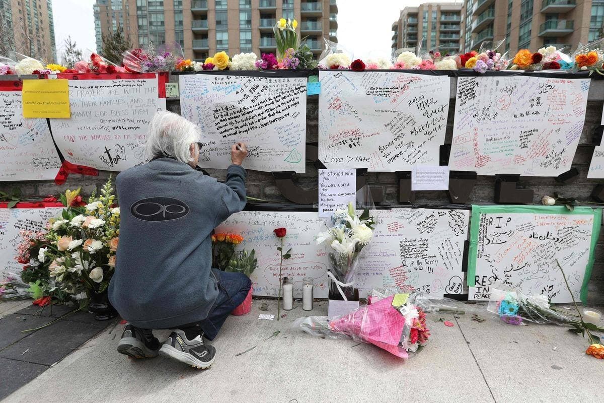 Un homme laisse une note sur le mémorial des victimes de l'attaque de Toronto.