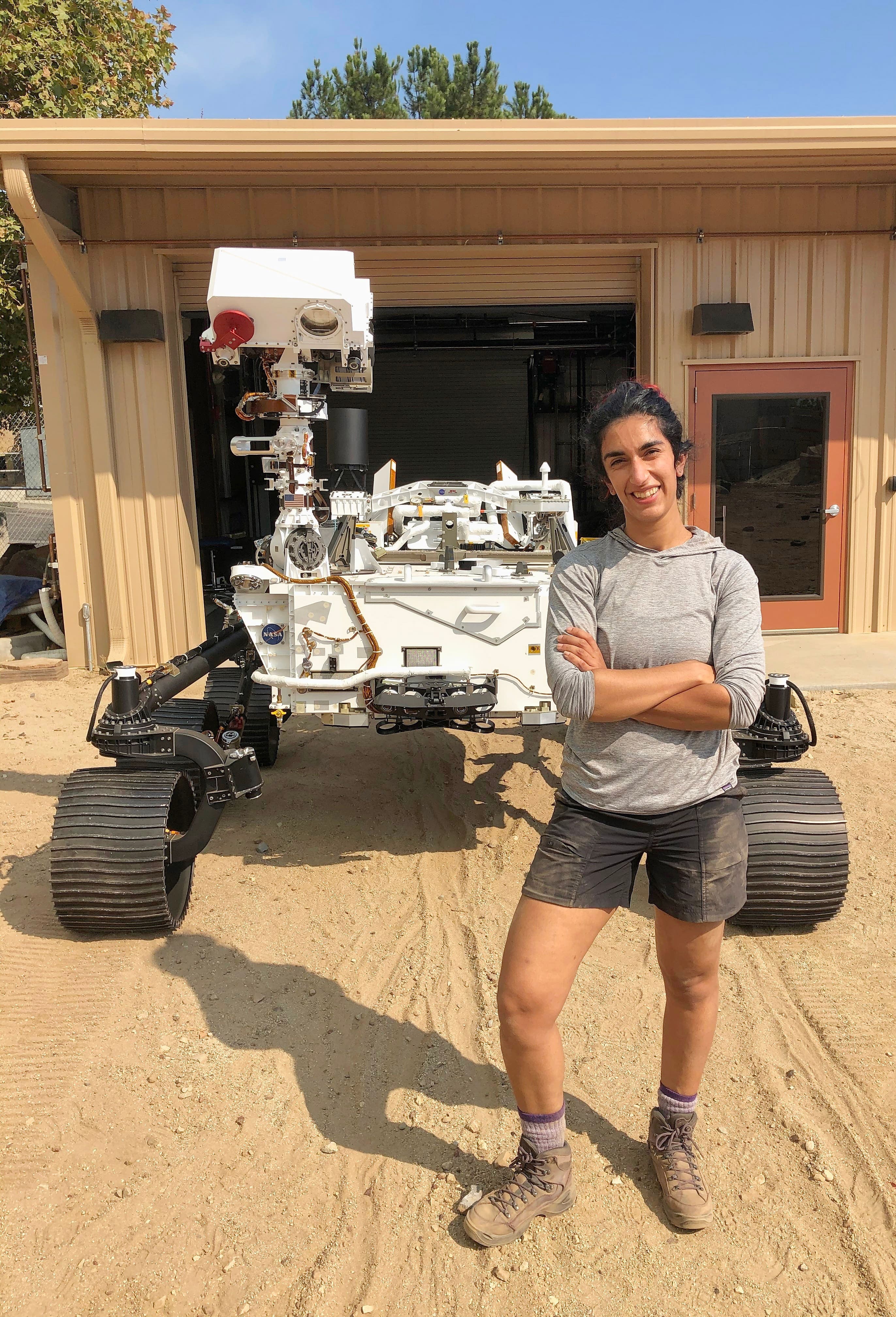 L’ingénieure québécoise Farah Alibay pose en compagnie du robot Perseverance dans le « champ de Mars », qui reproduit le sol martien, avant son départ pour la planète rouge.