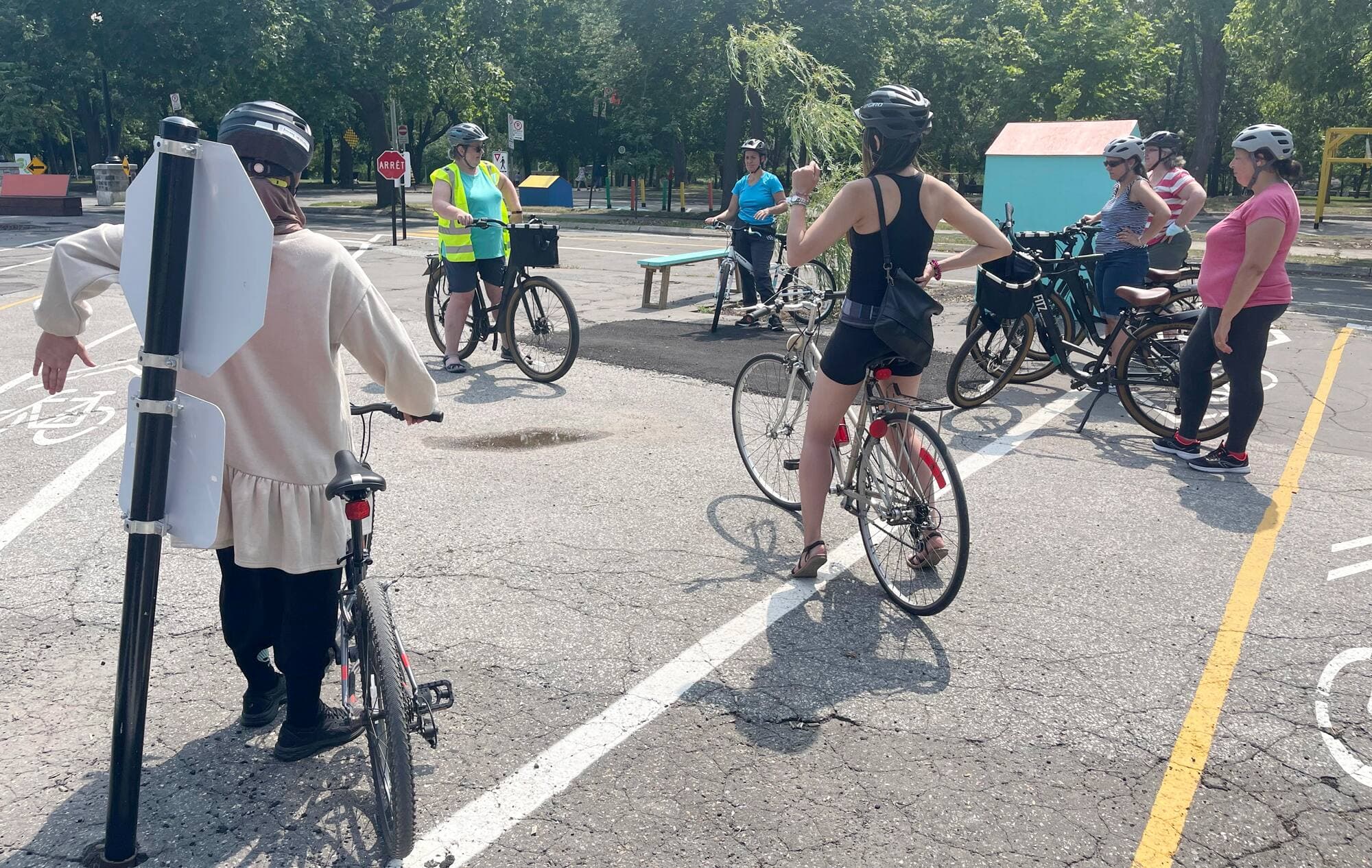Vêtue d’un dossard jaune, l’instructrice Joanne Boivin explique à son groupe comment freiner à vélo. La plupart utilisent leurs pieds pour ralentir et s’arrêter.