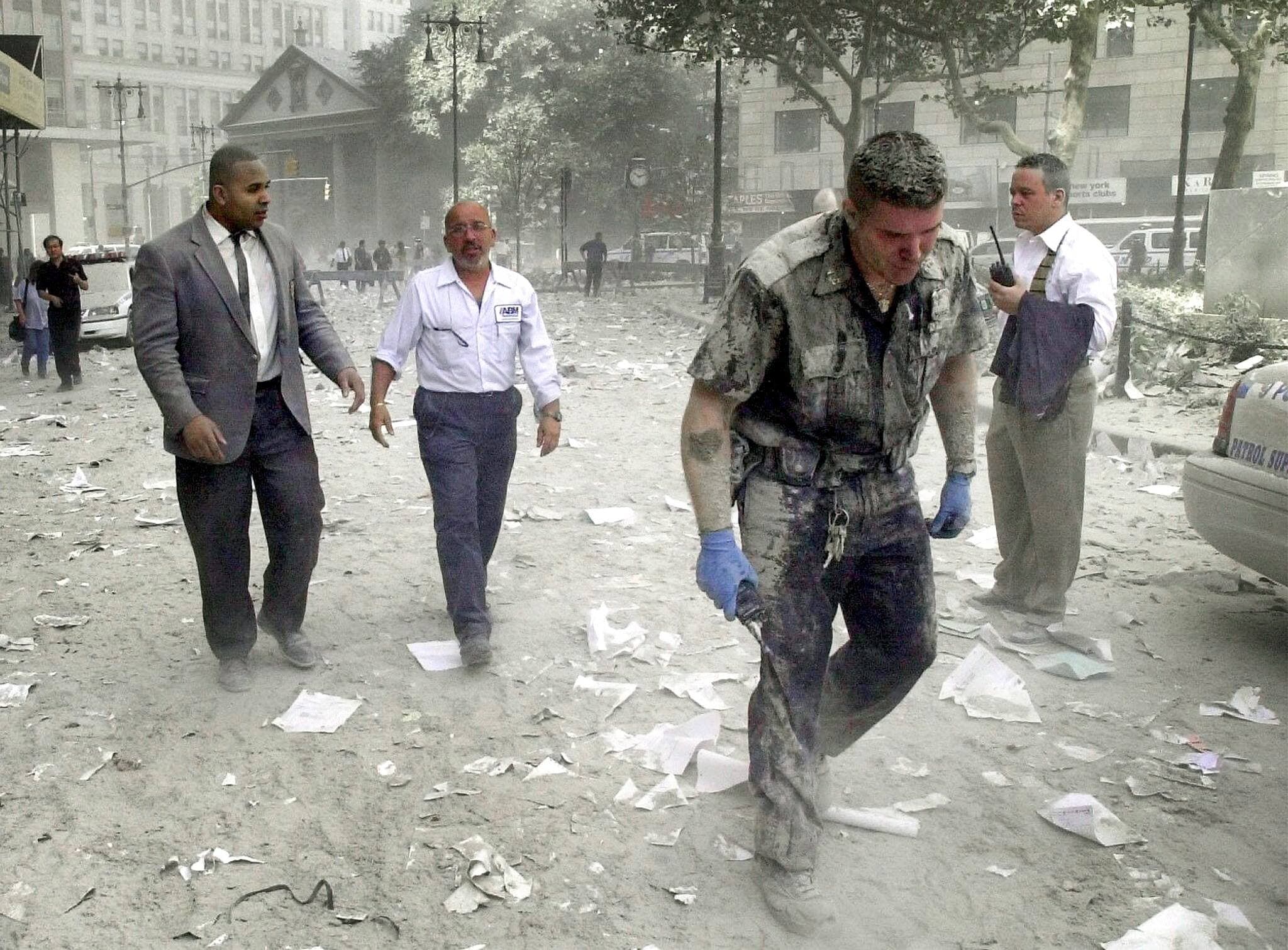 Un policier et d’autres citoyens erraient dans les décombres poussiéreux après l’effondrement des tours jumelles.