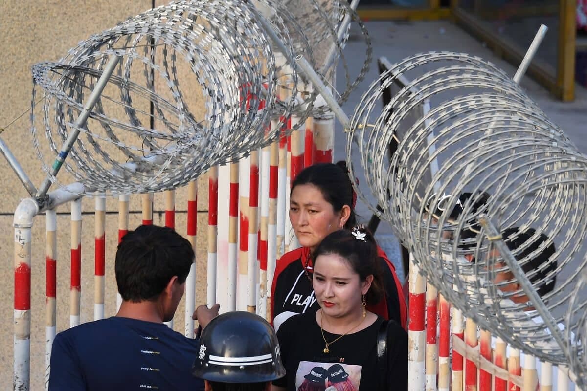 Photo prise le 31 mai 2019 montre une femme ouïghoure (au centre) traversant l'entrée d'un bazar à Hotan, dans la région du Xinjiang, au nord-ouest de la Chine