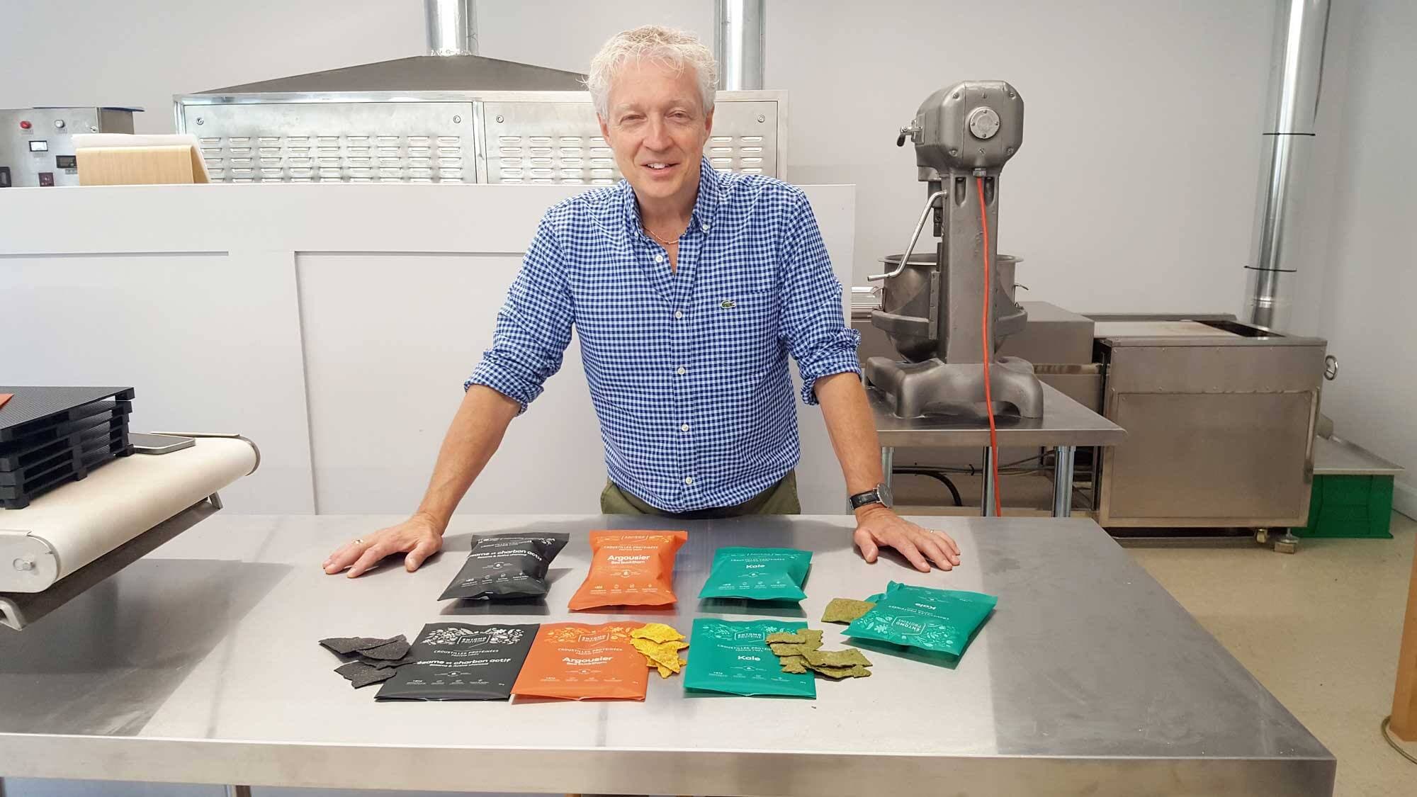Marco Poulin dans son usine de Cap-Santé devant ses trois saveurs de croustilles.