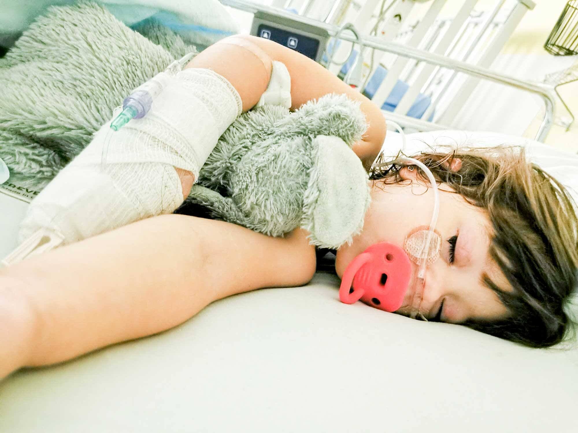 Amy sur son lit d’hôpital avec le soluté branché dans la main qui a engendré ses doigts tout noirs en raison d’un problème.