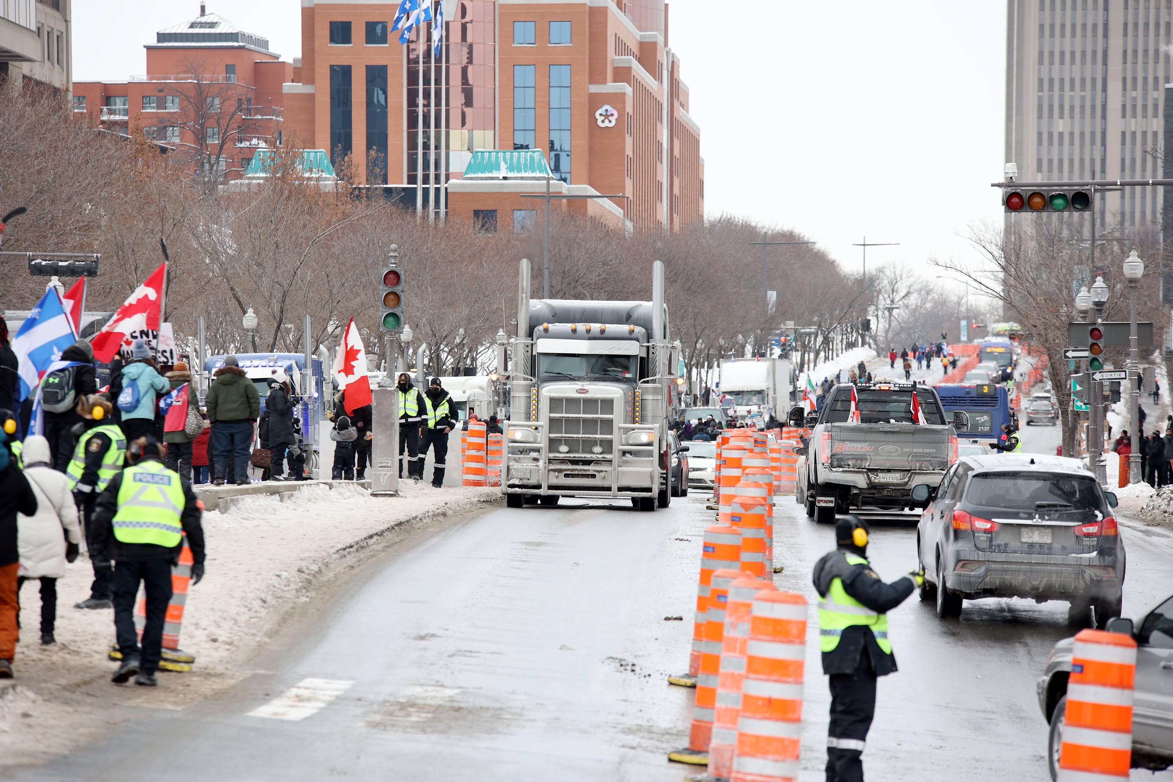 Des camions stationnés le long du boulevard René-Lévesque, près du parlement de Québec, sous forte surveillance policière. La collaboration entre le SPVQ et la SQ a été soulignée par un ancien policier.