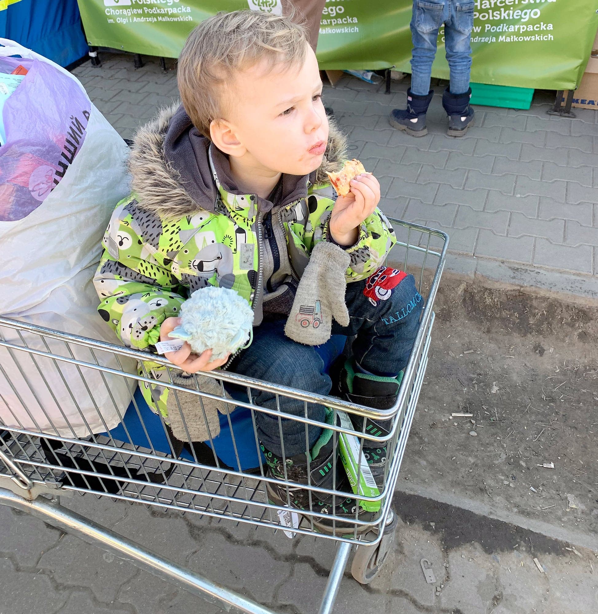 Un jeune garçon a profité du panier d’épicerie pour se reposer les jambes durant le passage de la frontière vers la Pologne.