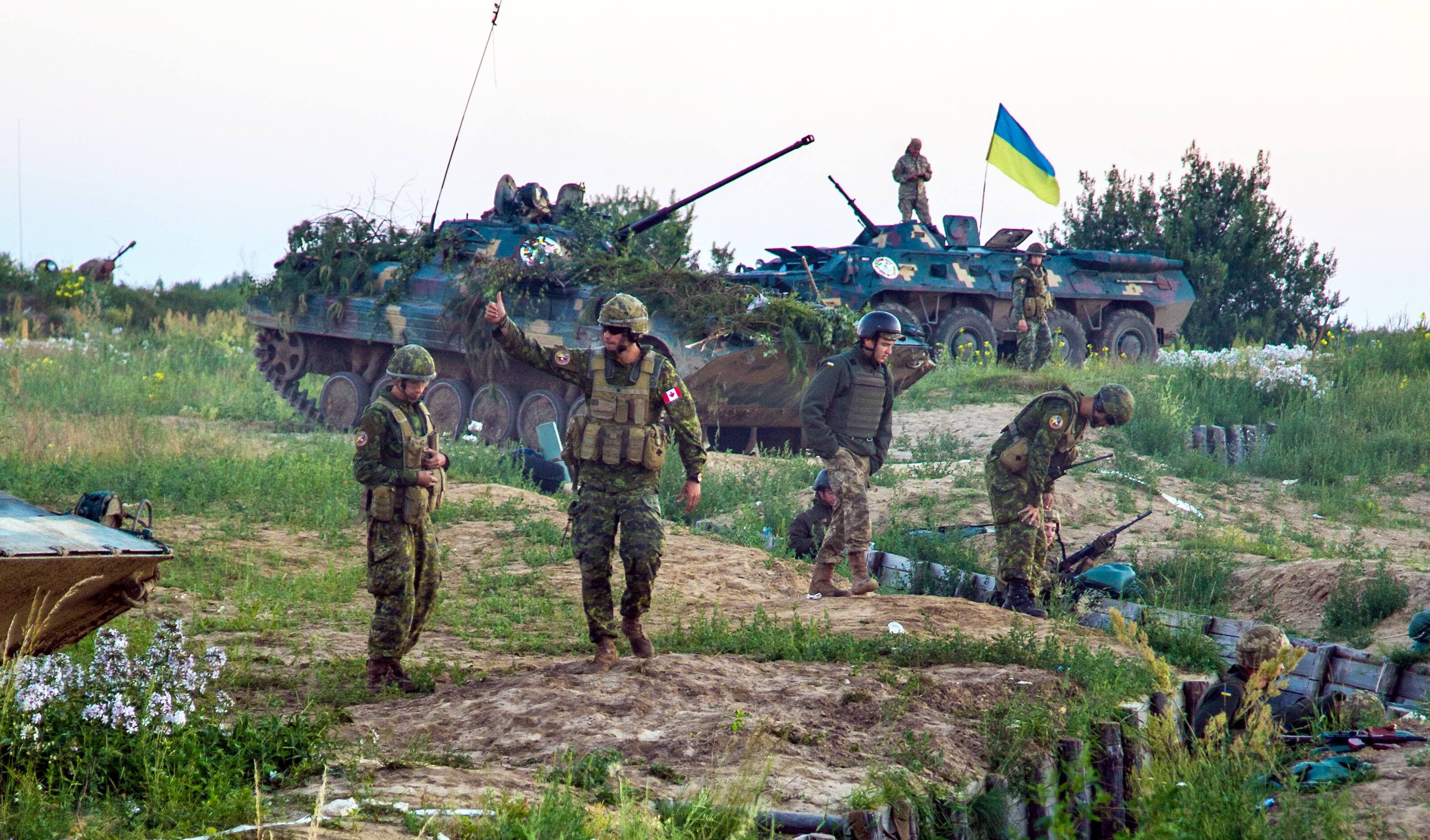 Un instructeur canadien salue les efforts des troupes ukrainiennes qui occupent une position défensive sur un champ de tir réel.
