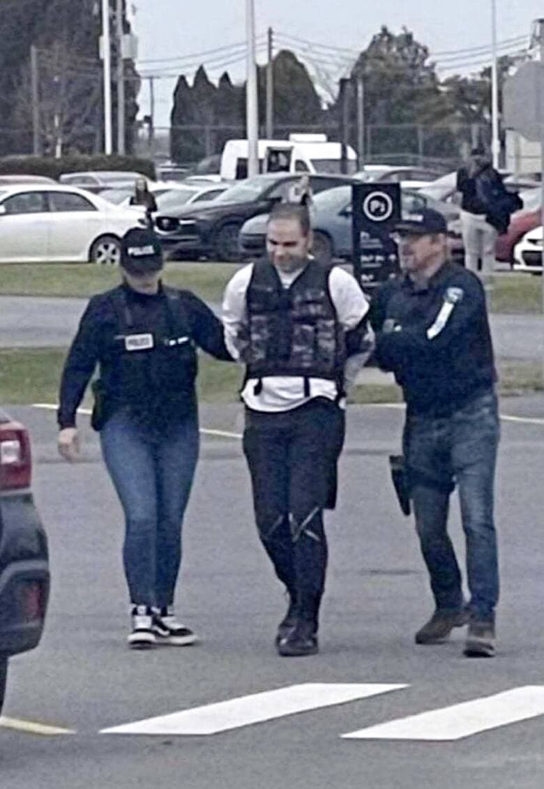 Simon-Olivier Frappier, escorté par des policiers, hors du cégep Saint-Jean-sur-Richelieu vendredi.