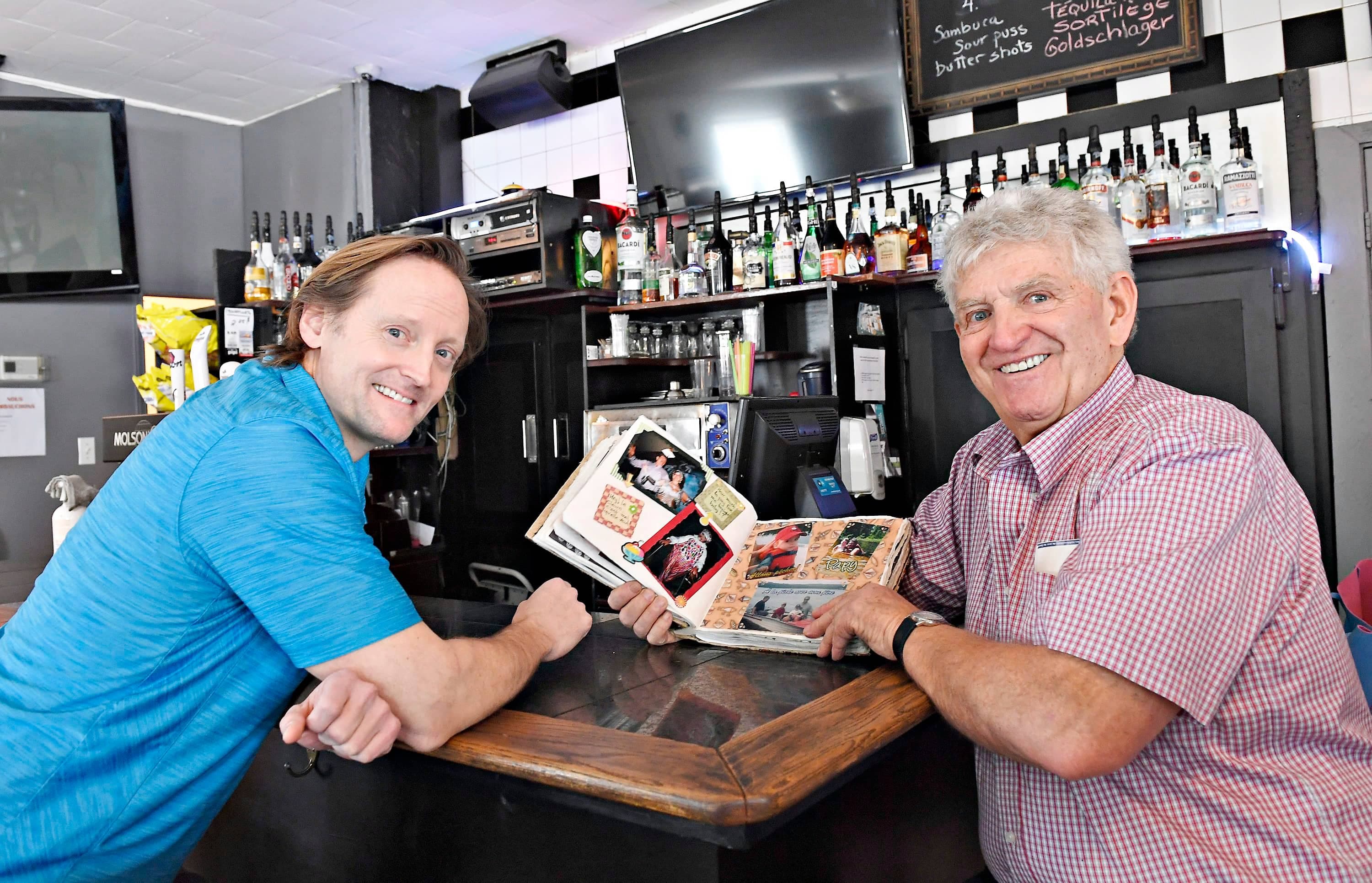 Propriétaire du bar Lionel depuis 50 ans, Guy Baillargeon (à droite) a conservé plusieurs photos au fil du temps, qu’il exhibe au futur propriétaire, Russell Eyestone, lequel conservera l’âme de l’établissement.