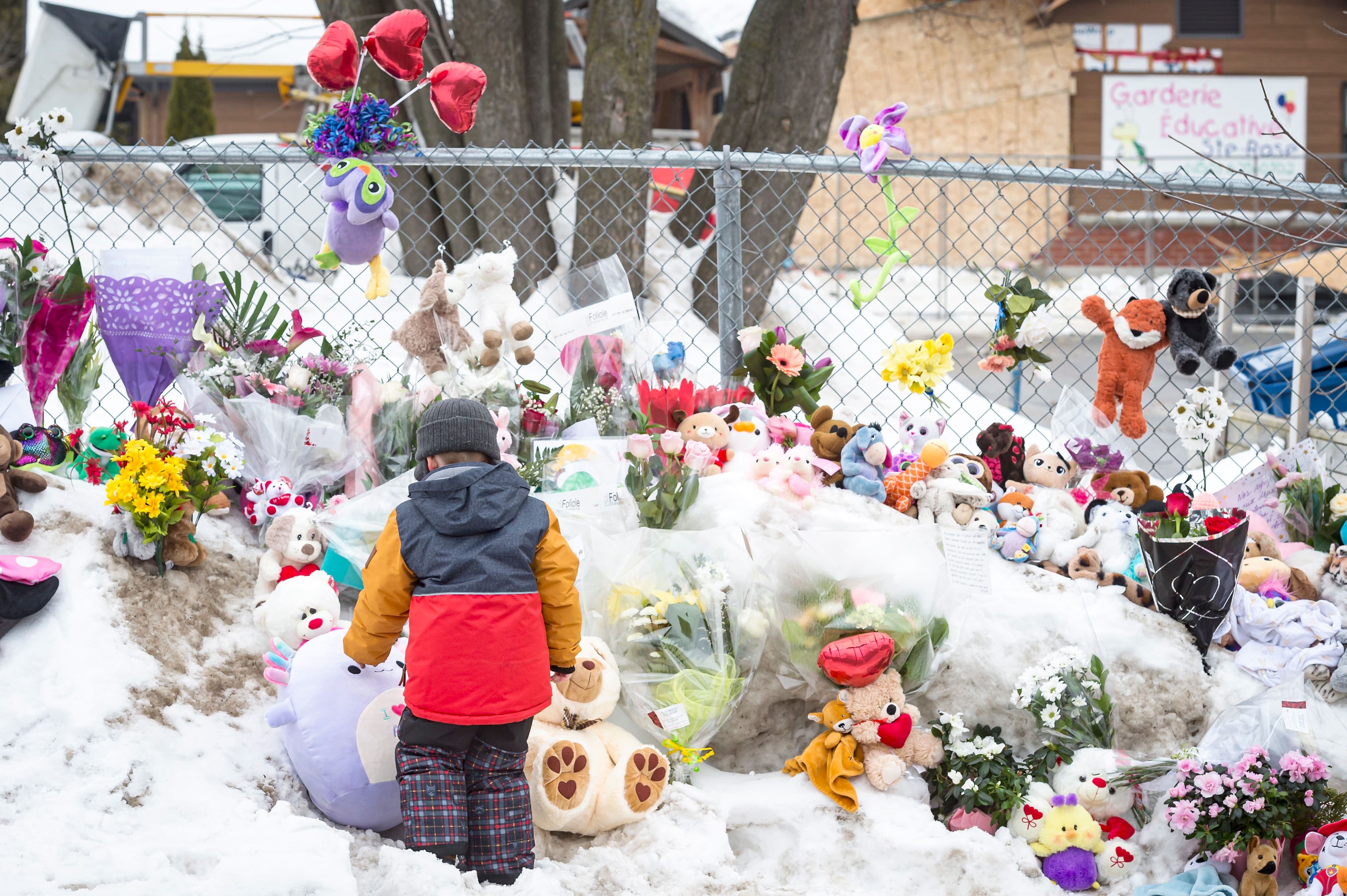 Devant la Garderie Éducative Ste-Rose un garçon a pris le temps de s’arrêter pour observer les fleurs et les peluches laissées en mémoire des enfants morts sous les roues de l’autobus mercredi.