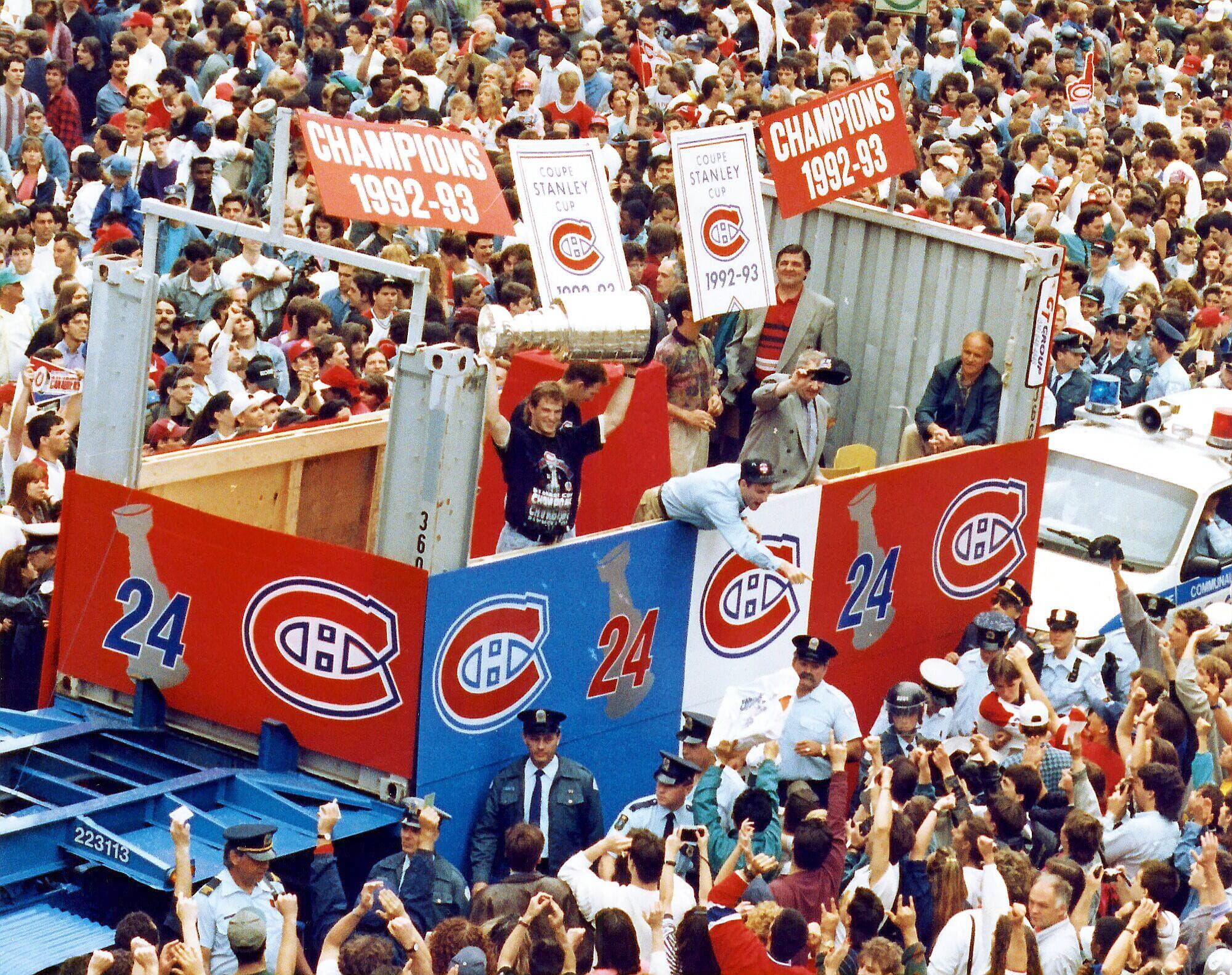 Kirk Muller lève la coupe Stanley à bout de bras sur le cortège aux couleurs du Canadien qui promènent les joueurs à travers Montréal, le 11 juin 1993, deux jours après leur triomphe aux dépens des Kings de Los Angeles. Dans les rues, des centaines de milliers de partisans acclament leurs champions.