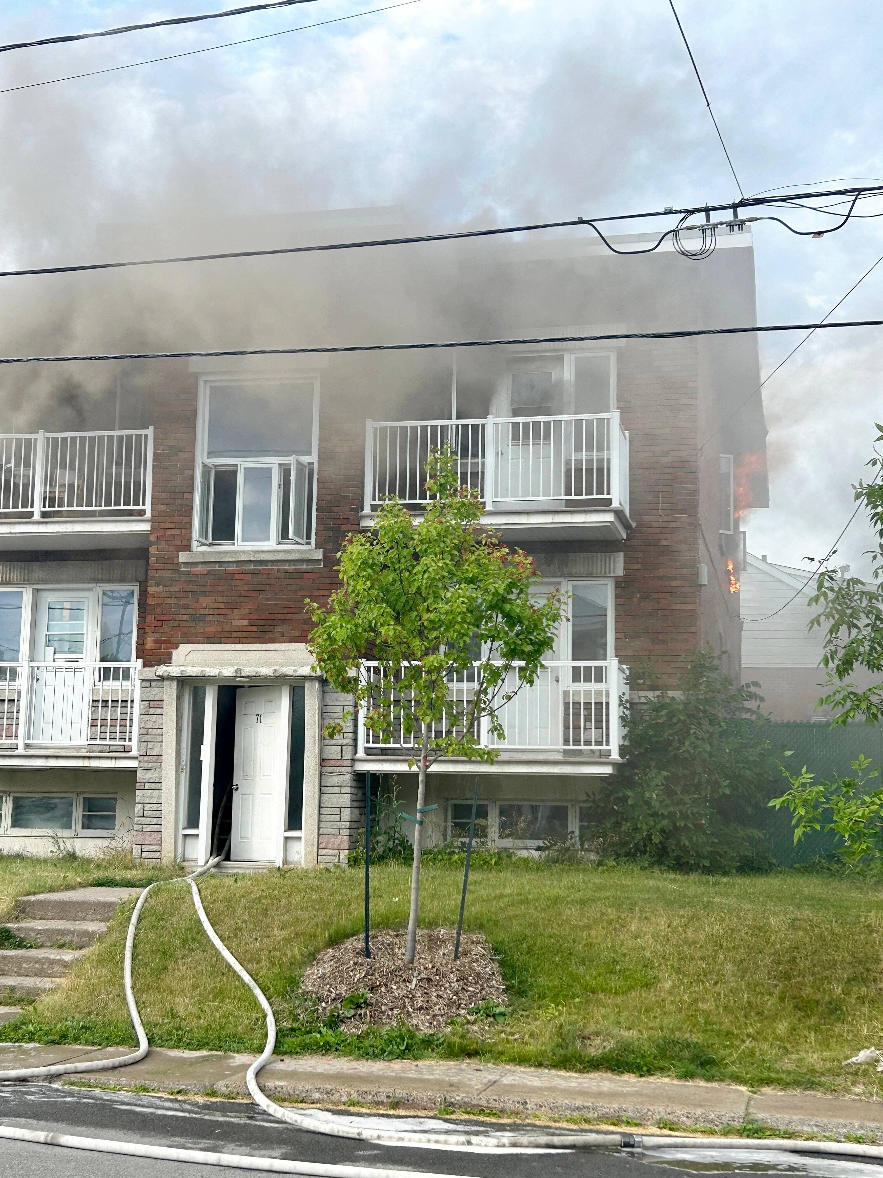 De la fumée et des flammes s’échappaient d’un immeuble à logements à l’intersection des rues Pontmain et Labelle, à Laval, le 1er juillet 2025.