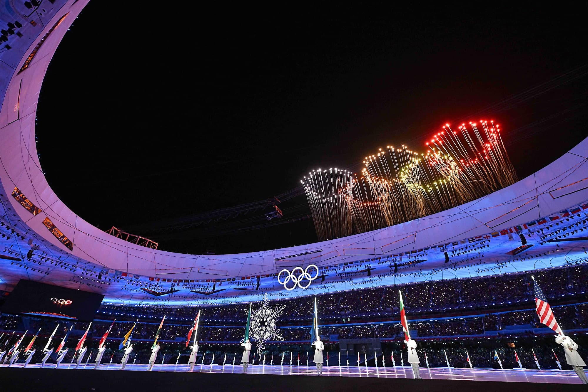 Des bénévoles tenaient les drapeaux des 91 pays ayant participé aux Jeux d’hiver de Pékin, dimanche, lors de la cérémonie de clôture haute en couleur.