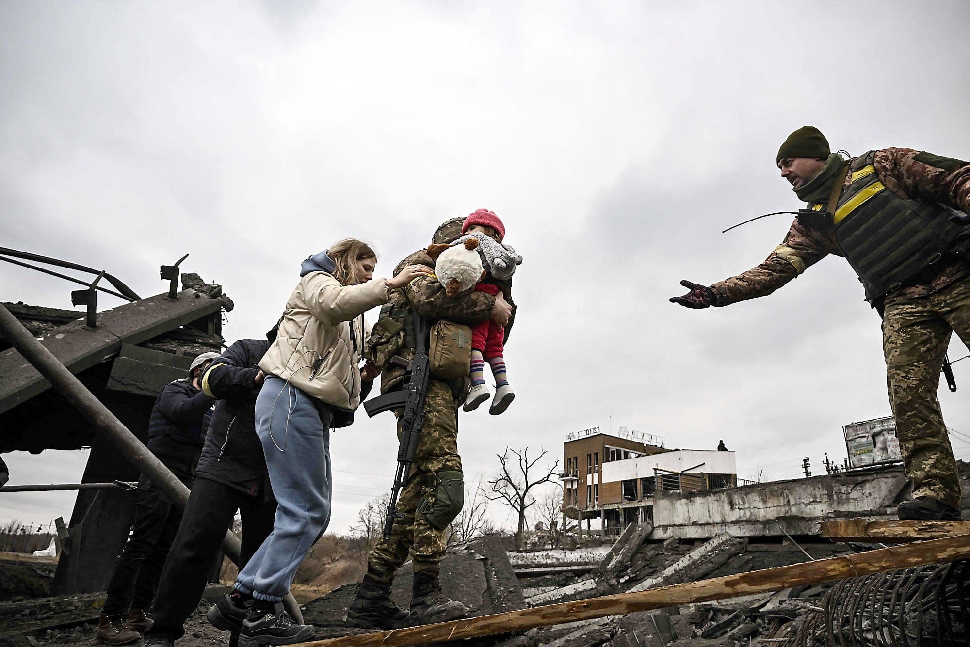 Un militaire ukrainien transporte un enfant tout en aidant les gens à traverser un pont détruit, alors qu’ils évacuent la ville d’Irpin, au nord-ouest de Kyïv.