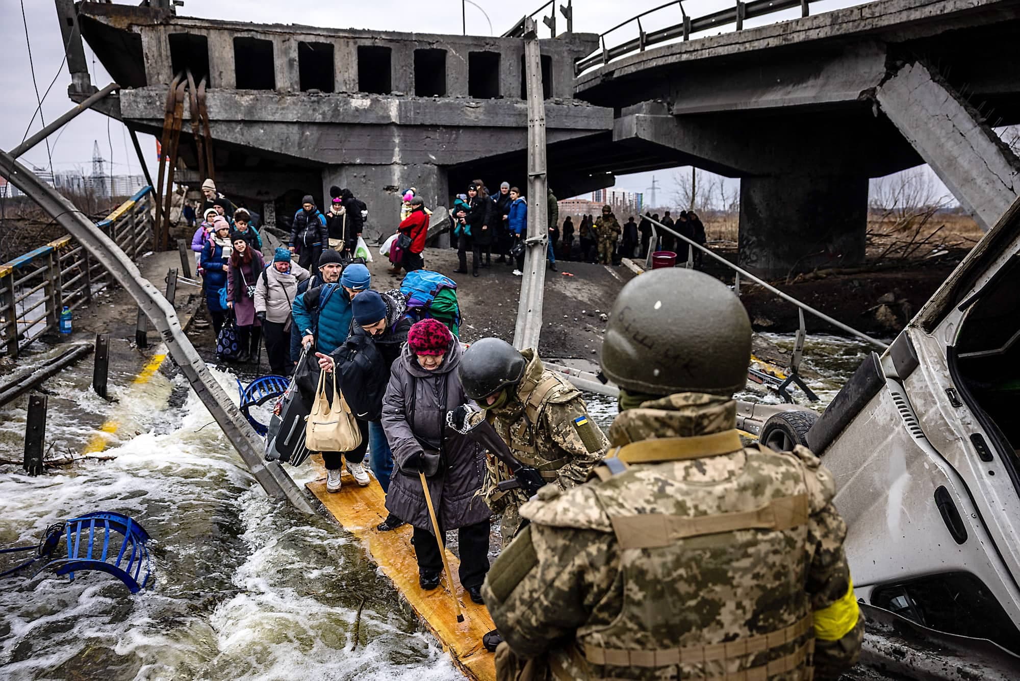 Des citoyens d’Irpin, au nord de Kyïv, évacuent leur village bombardé en empruntant un pont de fortune à la suite de la destruction du pont.