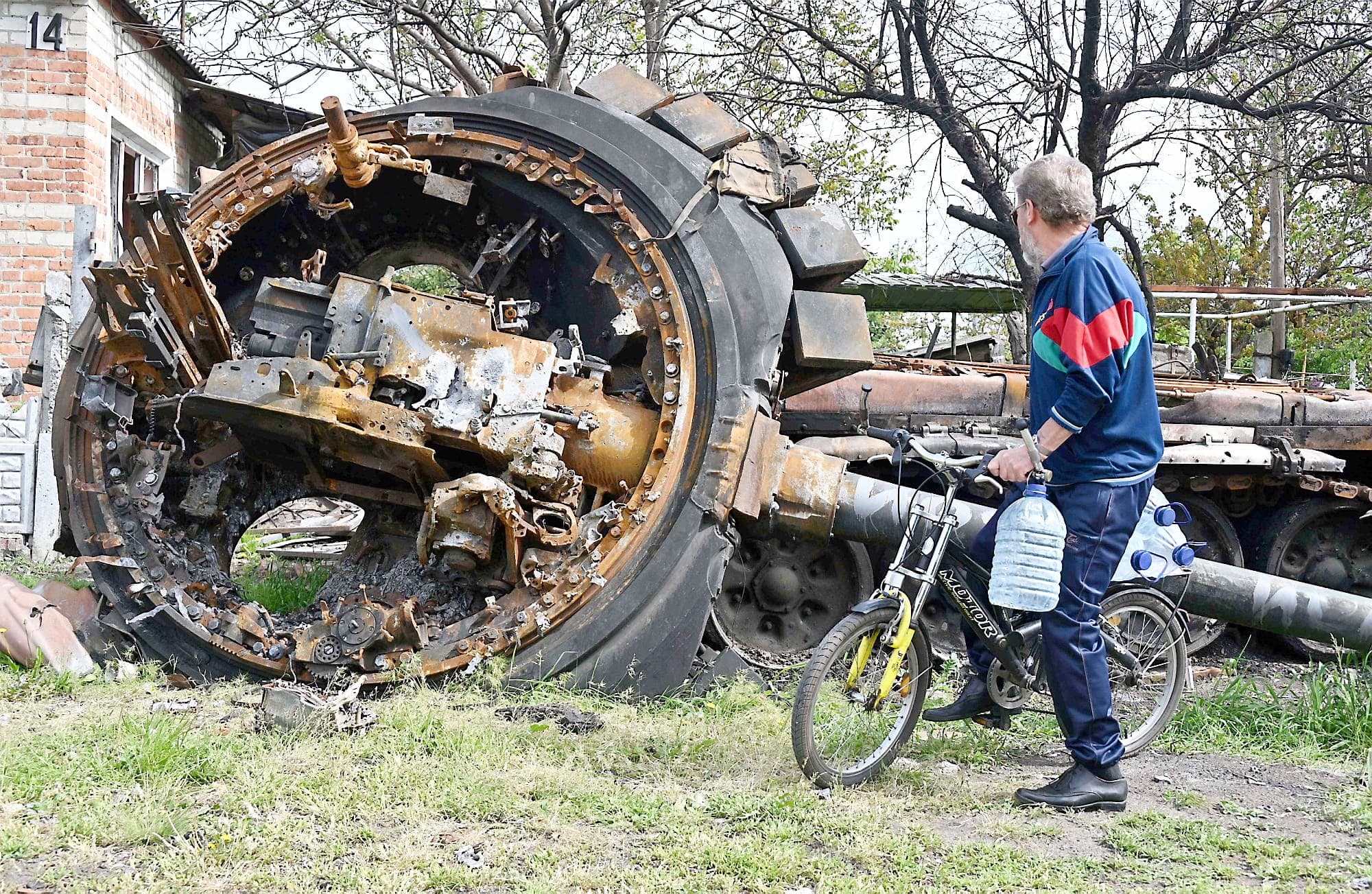 Un citoyen du village de Mala Rohan, à l’est de Kharkiv, devant un tank russe détruit situé tout près d’une maison, dimanche.