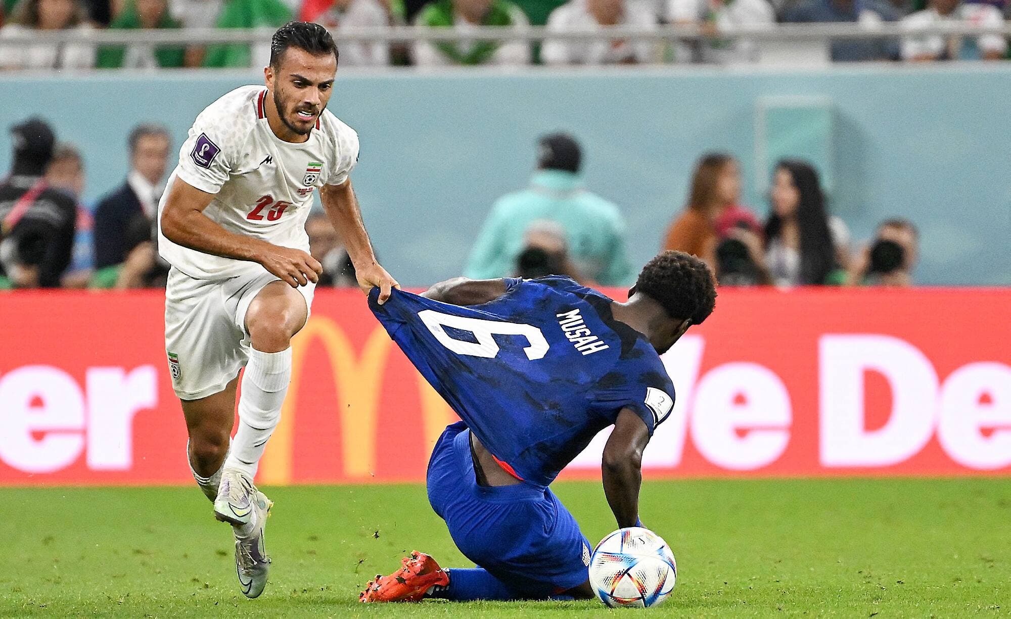 Le défenseur Abolfazl Jalali tire sur le chandail du milieu de terrain Yunus Musah en espérant le freiner.