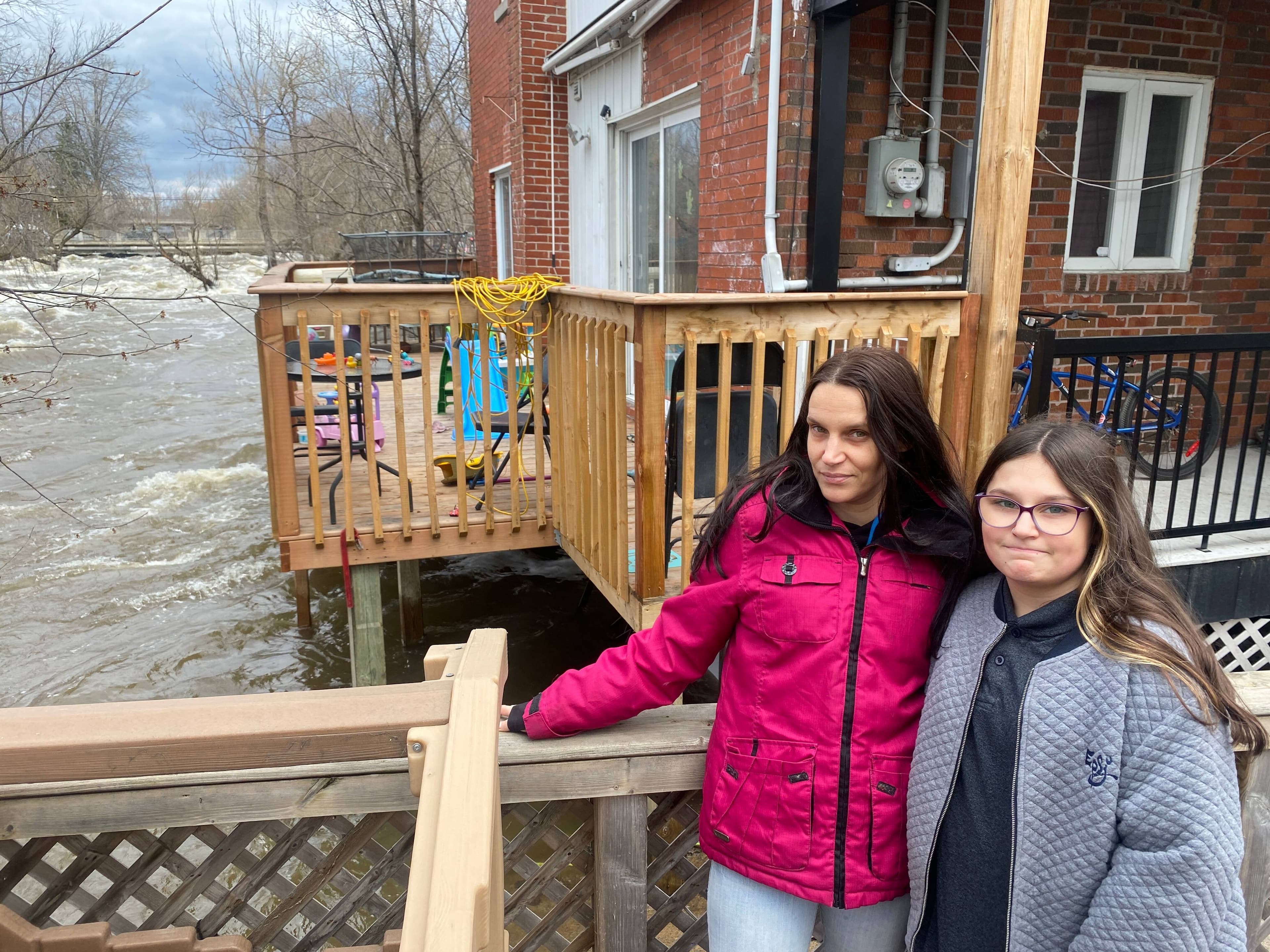 Kim Léonard et sa fille Lexcia Monette-Léonard dans leur cour inondée par la rivière du Nord à Saint-Jérôme.