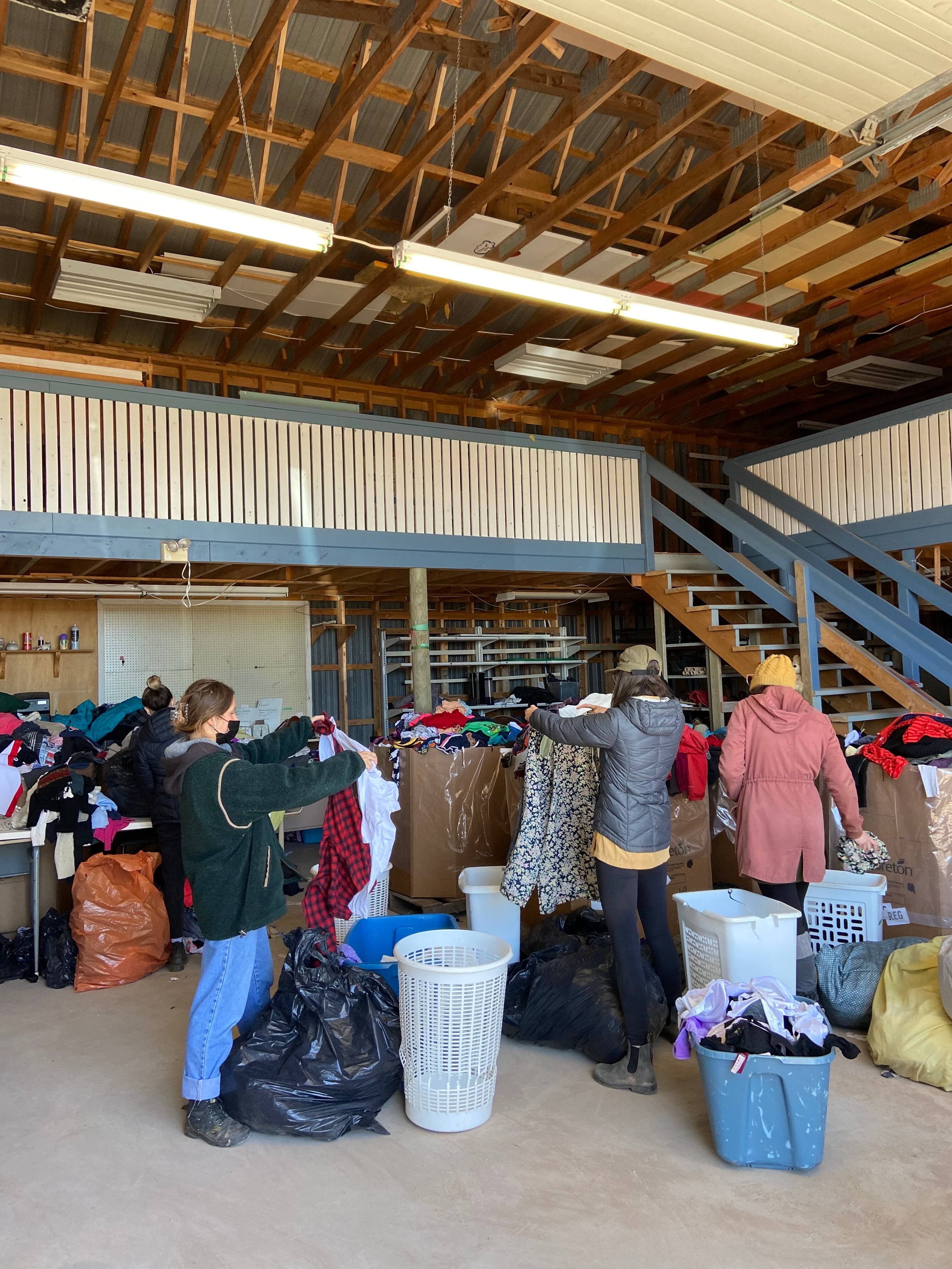 Les participantes à la « chasse au linge » trient plusieurs bacs de vêtements.