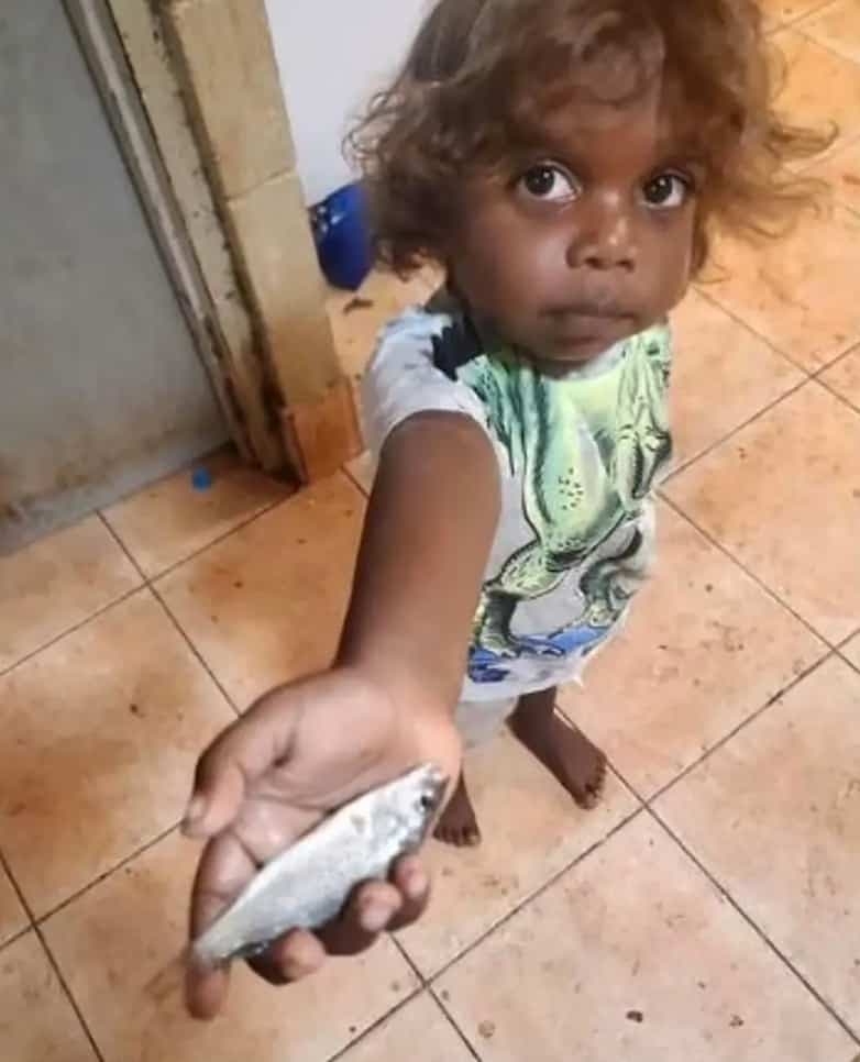 Une petite fille de la ville de Lajamanu en Australie tient un poisson tombé du ciel.