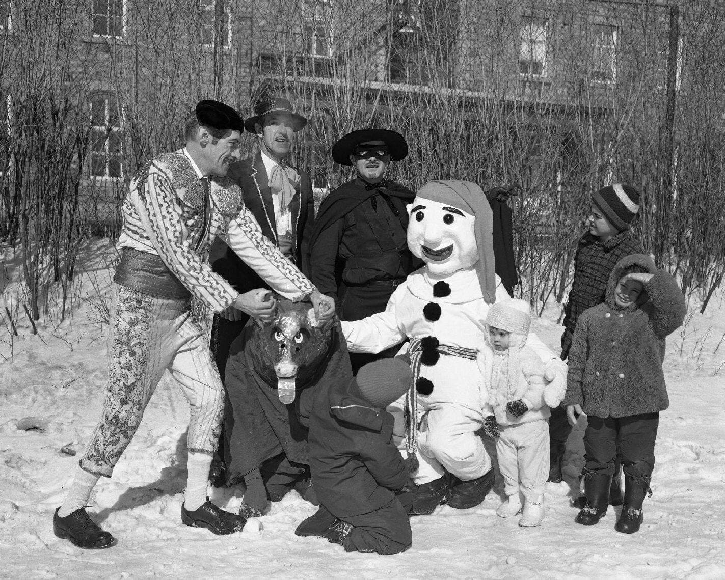 Sur cette photo prise lors du Carnaval Saint-Jean-Baptiste le 18 février 1963, on reconnaît un toréador, le Bonhomme et le personnage de Zorro. Mention spéciale au déguisement de taureau! BAnQ, P174,S1,D29553.
