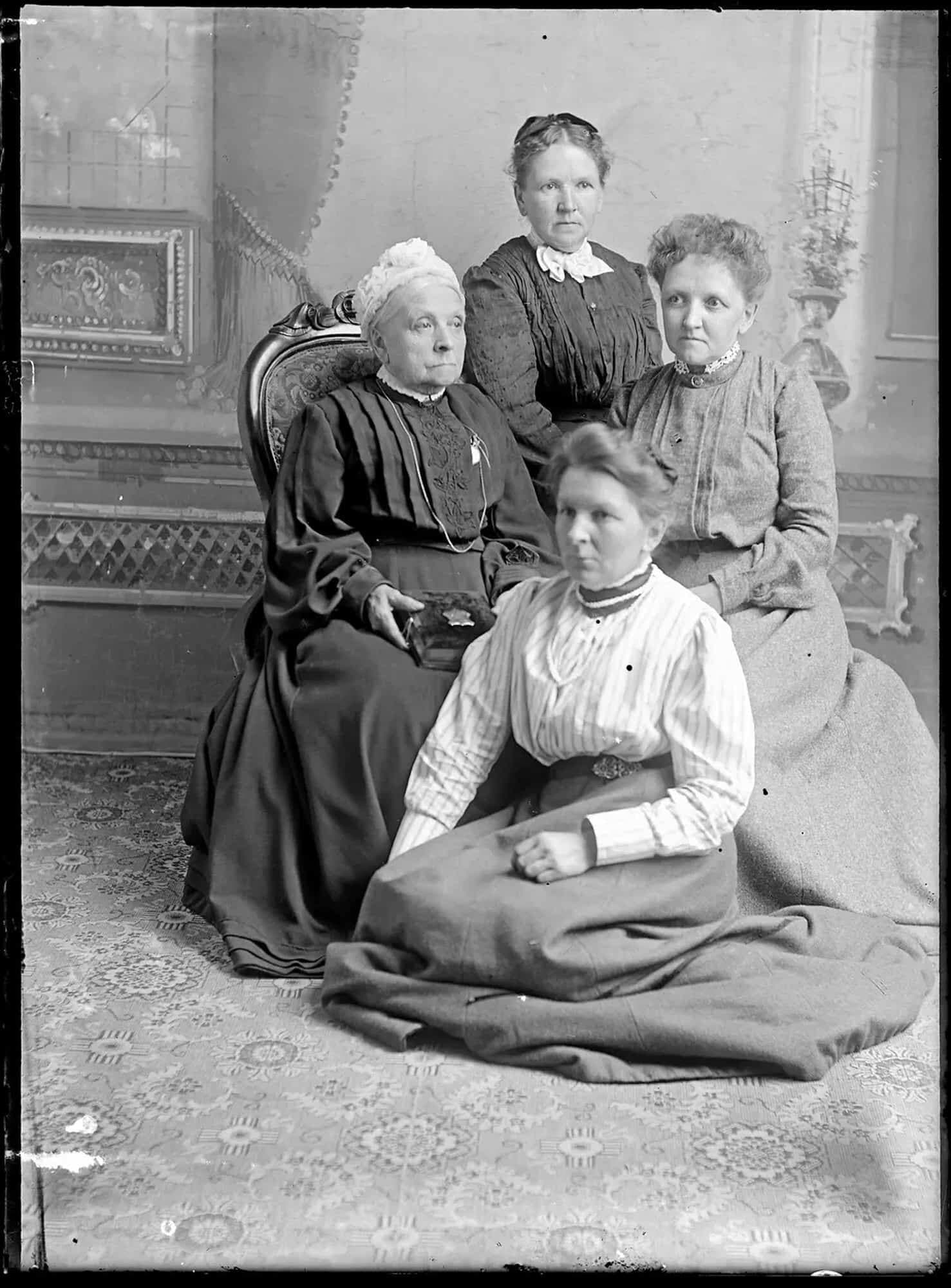 Sally Wood (assise par terre, dissimulant le déclencheur de l’appareil photo derrière sa jupe) en compagnie de sa mère et de ses deux sœurs.
