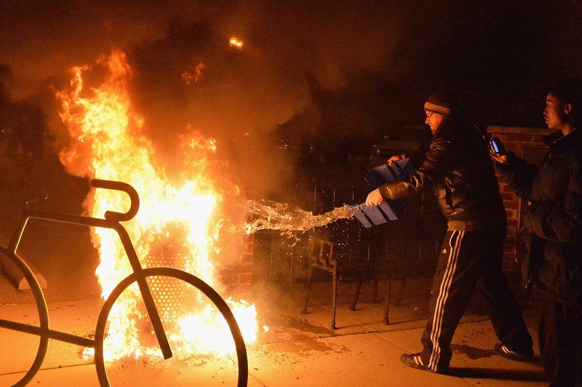 Des passants tentent d'éteindre une poubelle en feu, quelques mois après le décès de Michael Brown.